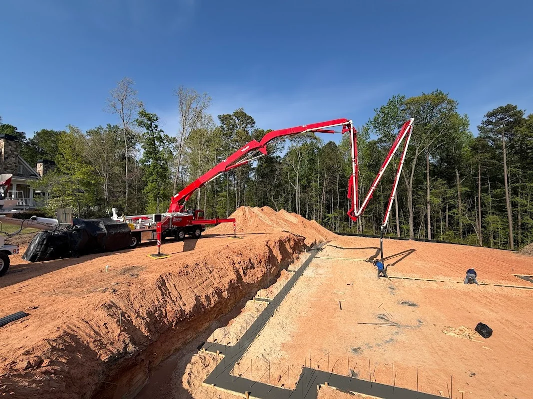Concrete pump boom arm extended over a residential slab form during an active pour.
